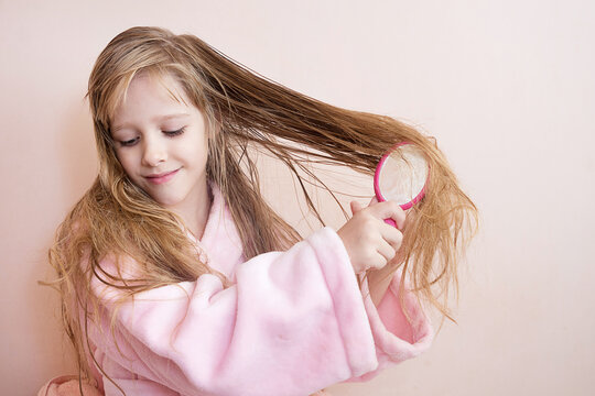 little girl combs her hair after a shower