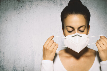 Female putting on protective face mask.