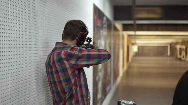 Man practicing using a rifle at shooting range in headphones