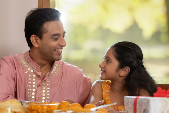 father looks at daughter with affection during Diwali celebrations 	