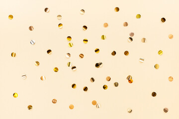 Gold confetti scattered on a beige background, top view. Color trend 2021, set sail champagne. Festive minimalistic background