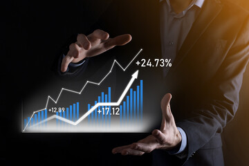 Business man holding holographic graphs and stock market statistics gain profits. Concept of growth planning and business strategy. Display of good economy form digital screen.