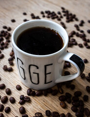 Cup of coffee with beans on wooden table