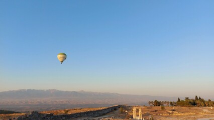 Hot air balloon in the blue sky over the ancient city of Hieropolis in Turkey in the morning. Flight over Pamukale. High quality photo