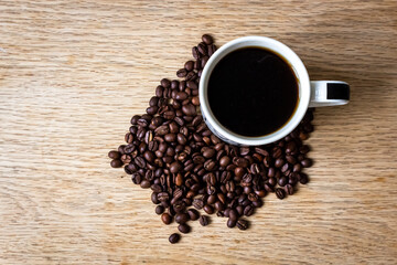 Cup of coffee with beans on wooden backround top view