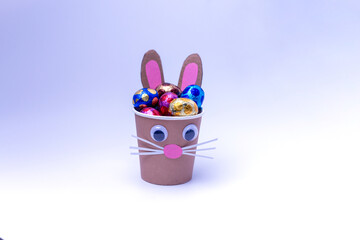 bunny craft from a paper cup filled with chocolate eggs in foil, holiday activity for kids