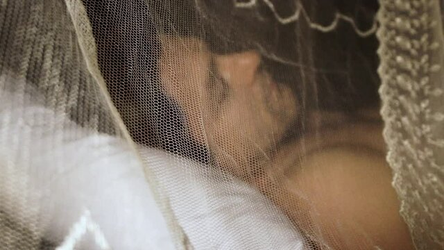 man lies under mosquito net at night