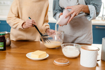 Caucasian beautiful mother and daughter making pancake dough