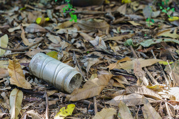 An old plastic jar was left in the garden with fallen leaves.