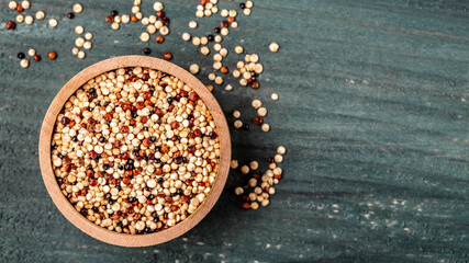 Quinoa seeds in wooden bowl on wooden background. Healthy and gluten free food. Long banner format, top view