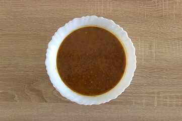 lentil soup in a white ceramic plate on a wooden surface - background ready to eat. Top view, soft focus at the background