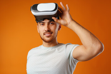 Casual man in white t-shirt wearing VR glasses against yellow background