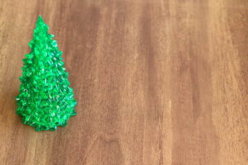 Glass Christmas tree close-up, on a light wooden background, with an empty space