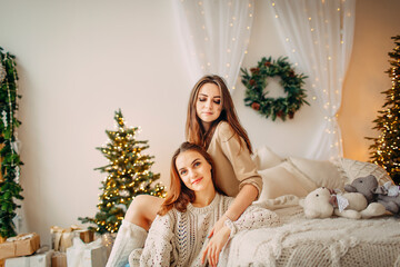 Obraz na płótnie Canvas two girls smiling and talking in christmas decorated bedroom