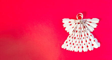 White angel made of paper on a red background. Copy space.