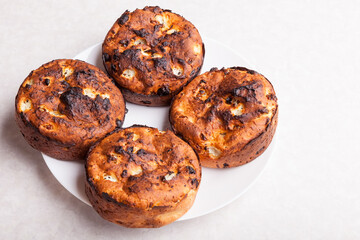 Top view of brown round flat-shaped cottage cheese buns on a plate on a white table - a hobby of baking desserts at home in the fall.
