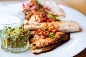 Delicious Mexican quesallidas made with chicken, tomato pieces and served with guacamole sauce.