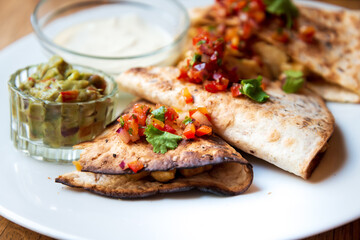 Delicious Mexican quesallidas made with chicken, tomato pieces and served with guacamole sauce.