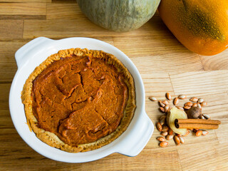 Homemade butternut squash pie with pumpkin spice, next to a kabocha and an orangetti squash, and...