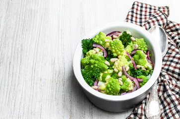 Romanesco cauliflower with capers and onion salad on white wooden table