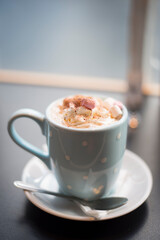 Burley, Hampshire, UK. An appealing mug of hot chocolate decorated with marshmallows in a polka dot mug with a spoon and saucer.