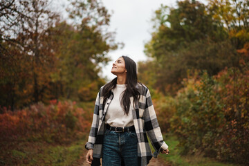 Beautiful happy woman smiling while strolling in autumn forest