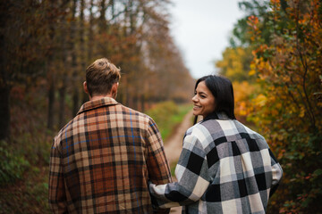 Beautiful happy couple smiling and hugging while strolling in forest