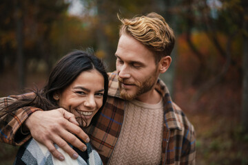 Beautiful happy couple smiling and hugging while strolling in forest