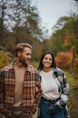 Beautiful happy couple smiling and hugging while strolling in forest