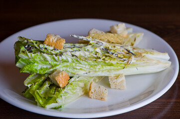 Caesar salad. Classic American salad with romaine, Caesar dressing, red onions, bacon lardons, Parmesan cheese, olive oil, lemon juice, salt and pepper. A Fine dining restaurant classic.