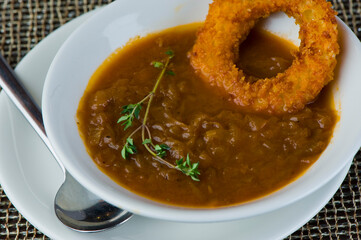 French Onion Soup. Classic traditional french restaurant bistro menu item. French onion soup, yellow onions reduced in broth topped with cheese melted and served with homemade baguettes. 