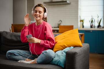 Nice joyful girl listening music with headphones and cellphone