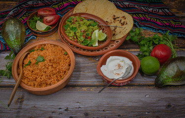 Traditional mexican rice, guacamole, corn tortillas on wooden background