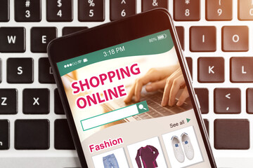 Mobile Phone With Online Shopping App Lying On Computer Keyboard