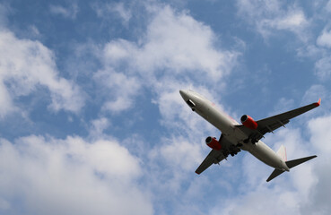 Fototapeta na wymiar Closeup of an airplane flying on the sky with cloudy blue sky background. 
