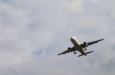 Fototapeta na wymiar Closeup of an airplane flying on the sky with cloudy sky background. 