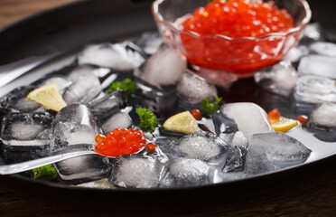 Fototapeta na wymiar red carviar with ice on black plate