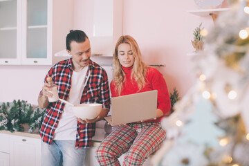 Portrait of a cheerful young couple cooking christmas meal together according to a recipe on a tablet computer