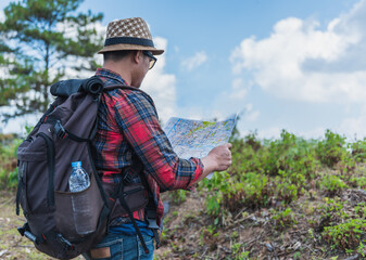 A young man looking at the map.Traveler with a backpack walking in the forest.
