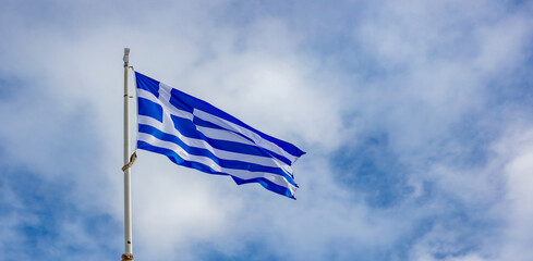 Greek flag waving against blue sky background.