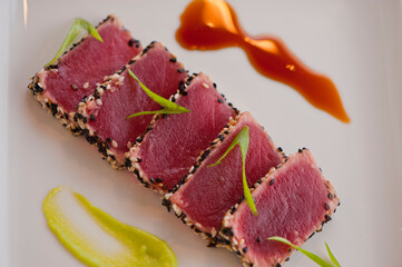 Ahi tuna, pan sesame seared rare. Premium sushi grade tuna seared and served with avocado, cucumber, caviar, ginger, wasabi and soy. Classic fine dining appetizer.