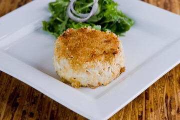 Crab cake. Crab served with spicy rémoulade sauce on top of a mixed green salad. Jumbo crab meat mixed with garlic, onions, spices & fried in butter. Classic American restaurant appetizer.