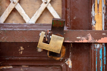 Heavy metal padlock closeup on a brown color entrance gate.