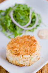 Crab cake. Crab served with spicy rémoulade sauce on top of a mixed green salad. Jumbo crab meat mixed with garlic, onions, spices & fried in butter. Classic American restaurant appetizer.