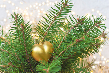 Christmas holiday composition. Golden heart and christmas lights on the christmas tree close up