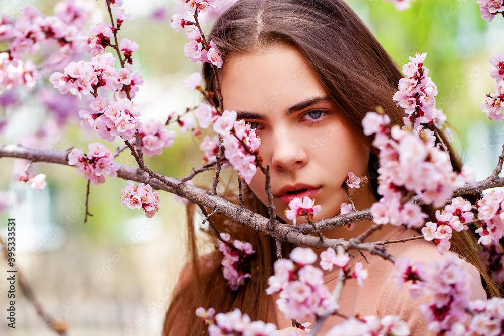 Wall mural pretty teen girl are posing in garden near blossom cherry tree with white flowers