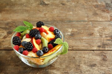 Fruit salad with berries on a wooden background with copy space
