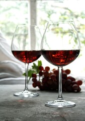 Two glasses of red wine with grapes bunch