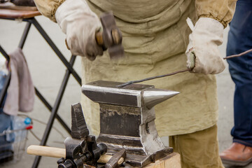 Blacksmith with a hammer on an anvil prepares a detail