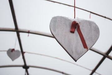 White heart with red ribbon outdoor. Hanging wooden heart. Romance and love concept. Valentines...